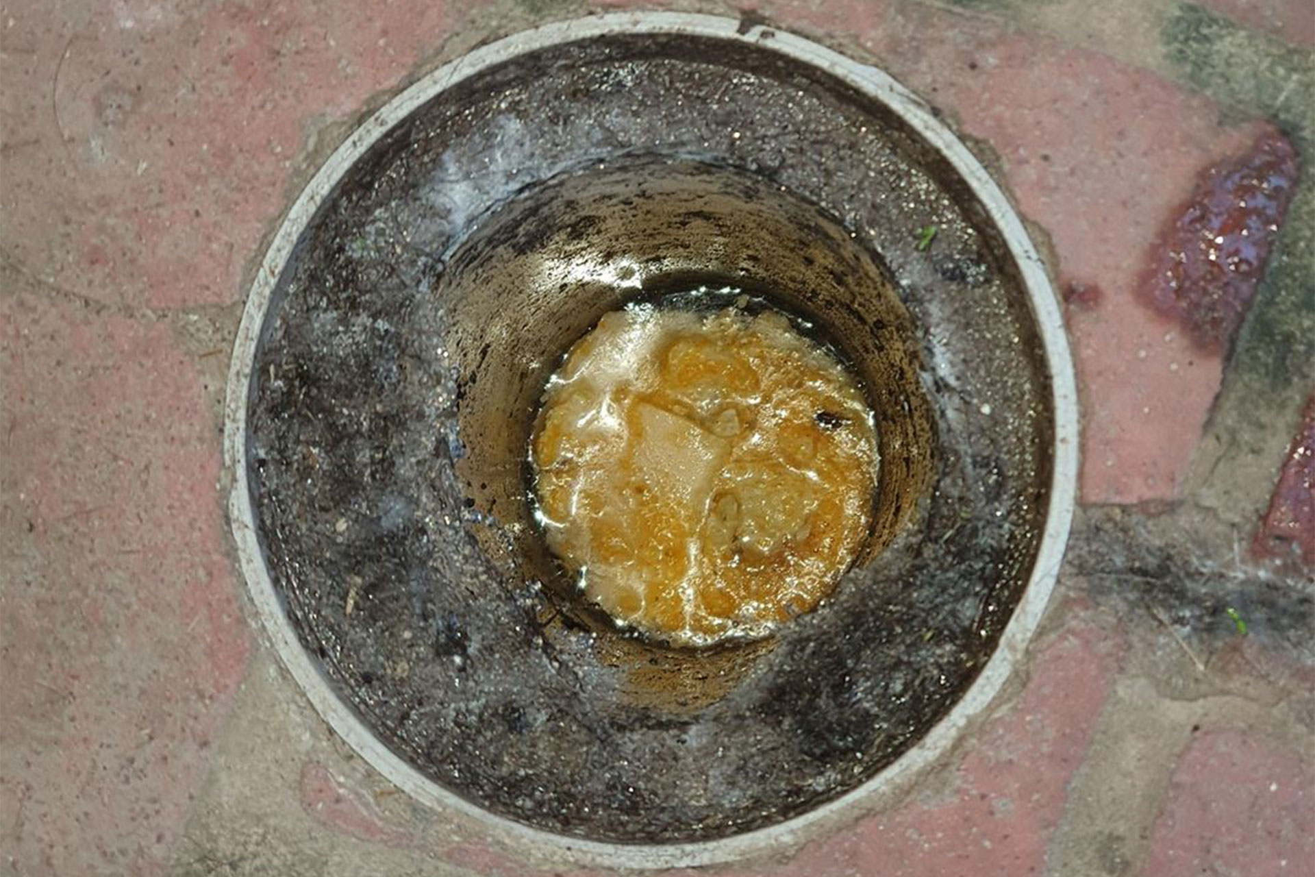 A drain blocked by oil and fat, common household items that don't belong down drains.